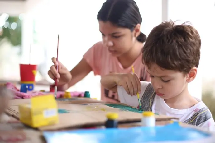 Crianças pintando juntas no programa de artes